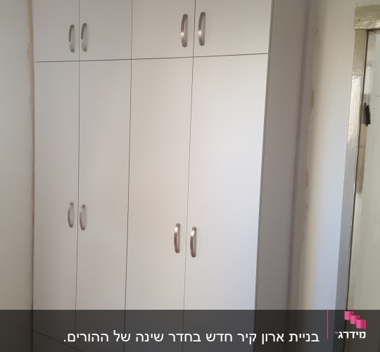 ארון לבן עם ידיות מתכת בחדר